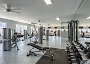 Thumbnail 23 of 35 - A spacious gym with a variety of equipment including treadmills, weights, and a bench press.