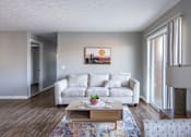 Thumbnail 33 of 66 - A living room with a white couch and a painting of a sunset on the wall.