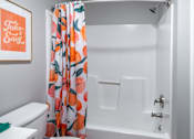 Thumbnail 28 of 66 - A white bathroom with a shower curtain and a toilet.