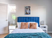 Thumbnail 38 of 66 - A bedroom with a large bed and a blue headboard.