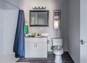 Thumbnail 27 of 66 - A bathroom with a white toilet and a blue shower curtain.