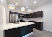 Thumbnail 8 of 27 - A kitchen with a white counter top and black cabinets.