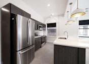 Thumbnail 7 of 27 - A modern kitchen with a stainless steel refrigerator and a white countertop.