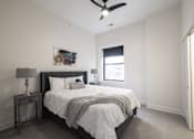 Thumbnail 19 of 27 - A bedroom with a bed, nightstand, and a ceiling fan.