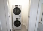 Thumbnail 22 of 27 - A white front load washing machine in a small laundry room.
