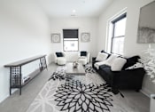 Thumbnail 14 of 27 - A black and white living room with a rug and a couch.