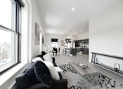 Thumbnail 15 of 27 - A modern living room with a black couch and a large window.