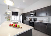 Thumbnail 2 of 27 - A modern kitchen with a white countertop and black cabinets.