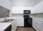 Thumbnail 5 of 50 - a kitchen with white cabinets and black appliances and a sink at Centerpointe Apartments, New York