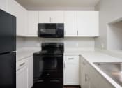 Thumbnail 1 of 50 - a kitchen with black appliances and white cabinets at Centerpointe Apartments, Canandaigua, New York