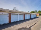 Thumbnail 39 of 50 - a row of garages with blue garage doors and brick at Centerpointe Apartments, Canandaigua, NY