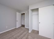 Thumbnail 12 of 50 - a bedroom with white walls and carpet and a door to a closet at Centerpointe Apartments, Canandaigua, NY