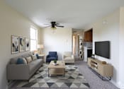 Thumbnail 32 of 35 - A living room with a grey couch, a blue chair, a coffee table, and a television.