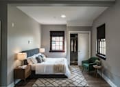 Thumbnail 11 of 29 - A bedroom with a large bed and a green chair.