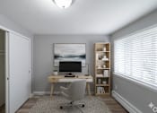 Thumbnail 16 of 17 - A room with a desk, chair, and a painting on the wall.