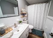 Thumbnail 28 of 35 - A bathroom with a white shower curtain and a white toilet.
