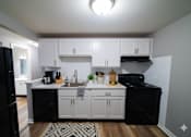 Thumbnail 31 of 35 - A kitchen with black appliances and white cabinets.