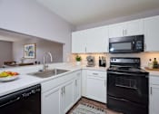 Thumbnail 4 of 77 - A modern kitchen with white cabinets and black appliances. at CenterPointe Apartments & Townhomes, Canandaigua, NY, 14424