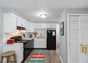 Thumbnail 4 of 17 - A kitchen with black appliances and white cabinets.