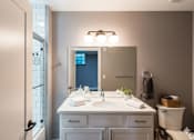 Thumbnail 14 of 29 - A bathroom with a white vanity and a mirror above it.