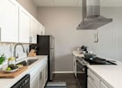 Thumbnail 7 of 47 - A modern kitchen with white cabinets and stainless steel appliances.
