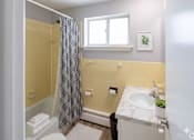 Thumbnail 14 of 17 - A bathroom with a yellow tiled shower and a white sink.
