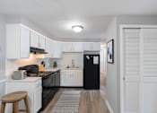 Thumbnail 5 of 17 - A kitchen with black appliances and white cabinets.