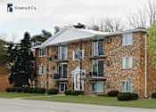 Thumbnail 2 of 35 - A brick building with a white picket fence in front.