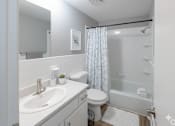 Thumbnail 13 of 17 - A white bathroom with a sink, toilet, and shower.