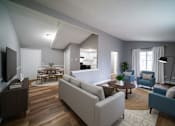 Thumbnail 17 of 35 - A living room with a grey couch and a wooden floor.