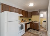 Thumbnail 8 of 17 - A kitchen with white appliances and wooden cabinets.