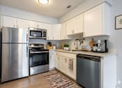 Thumbnail 1 of 25 - A kitchen with a refrigerator, oven, microwave, and dishwasher.at Fernwood Grove Apartments, Tampa, FL, 33614