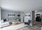 Thumbnail 11 of 17 - A living room with a white couch, a coffee table, and a chair.