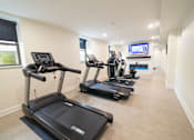 Thumbnail 24 of 27 - A spacious room with treadmills and a television.