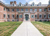 Thumbnail 27 of 29 - A large brick building with a long walkway in front.