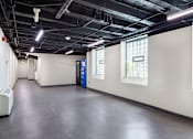 Thumbnail 19 of 29 - A large, empty room with a blue door and windows on the wall.