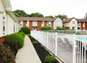 Thumbnail 52 of 61 - a white picket fence separates a sidewalk from a pool in an apartment complex