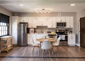 Thumbnail 6 of 29 - A modern kitchen with a dining table and chairs.