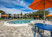 Thumbnail 33 of 47 - A round table with a blue tablecloth is in the foreground of a pool area.