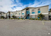 Thumbnail 39 of 47 - A parking lot in front of a building with a blue sky and clouds in the background.