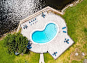 Thumbnail 35 of 47 - An aerial view of a swimming pool surrounded by lawn chairs and trees.