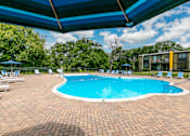 Thumbnail 48 of 55 - A swimming pool surrounded by a brick patio and lounge chairs under a blue canopy.