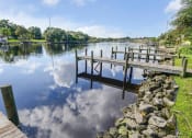 Thumbnail 21 of 47 - a dock on a lake with a blue sky and clouds reflected in the water