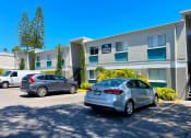 Thumbnail 33 of 47 - a large grey building with two cars parked in front of it