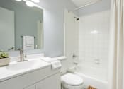 Thumbnail 9 of 25 - A white bathroom with a toilet, sink, and shower.at Fernwood Grove Apartments, Tampa, 33614