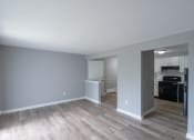 Thumbnail 6 of 15 - an empty living room with wood floors and a kitchen