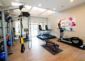 Thumbnail 38 of 49 - A gym with a variety of equipment including a treadmill, rowing machine, and weight machines.