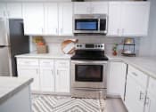 Thumbnail 5 of 36 - a white kitchen with a stove and a microwave