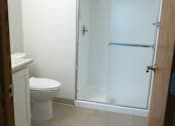 Thumbnail 22 of 49 - A white toilet sits in a small bathroom with a walk-in shower.