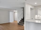 Thumbnail 8 of 36 - A white room with a staircase and a kitchen area.
